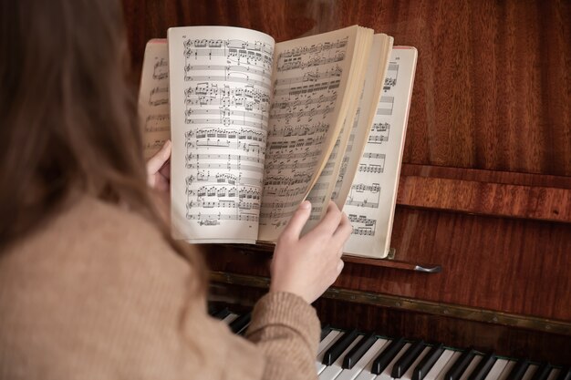 La mujer al piano hojea una colección de notas