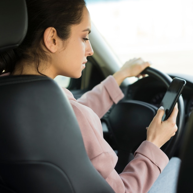 Mujer al volante usando su teléfono