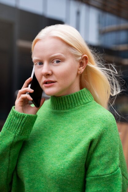 Mujer albina de tiro medio hablando por teléfono