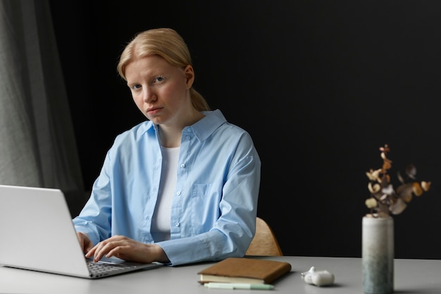 Mujer albina de tiro medio trabajando en una computadora portátil