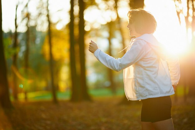 Mujer alegre activa corriendo en el parque local