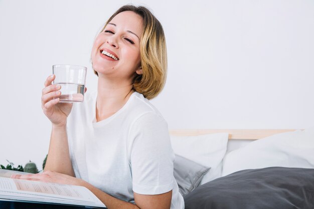 Mujer alegre con agua leyendo revistas