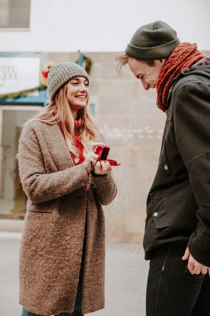Mujer alegre con anillo proponiendo al hombre en la calle