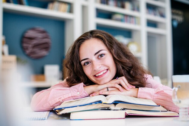 Mujer alegre apoyándose en libros