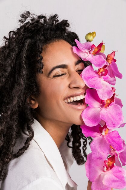 Mujer alegre atractiva con la flor de la orquídea