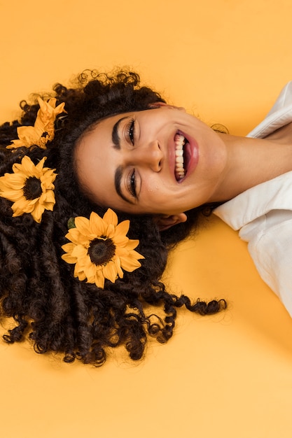 Mujer alegre atractiva con flores en el pelo