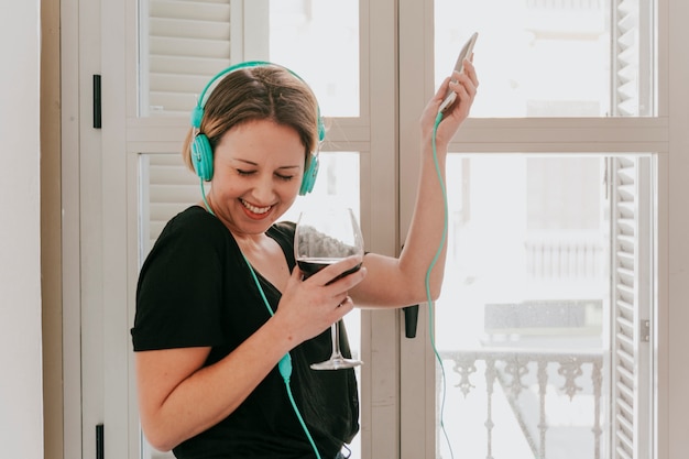 Foto gratuita mujer alegre en auriculares con vino