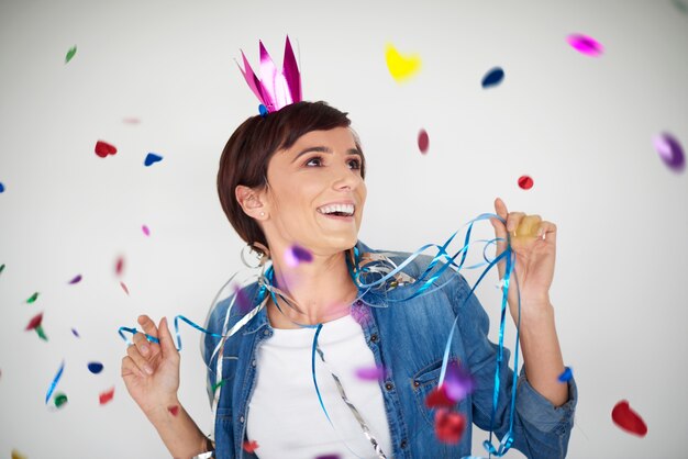 Mujer alegre bailando entre piezas de confeti de colores