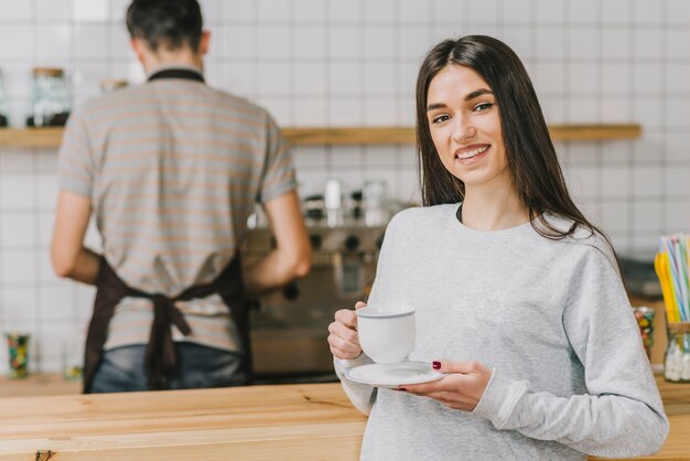 Mujer alegre bebiendo en café