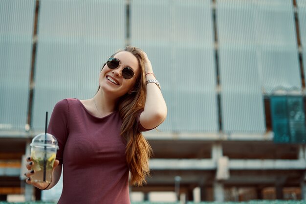 Mujer alegre en la calle bebiendo mañana refrescante bebida