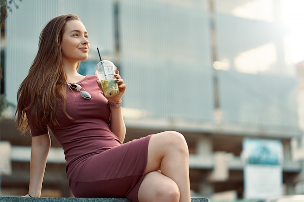 Mujer alegre en la calle bebiendo mañana refrescante bebida