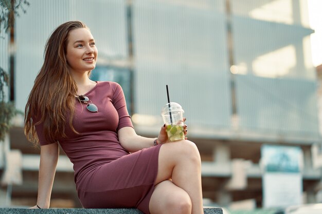 Mujer alegre en la calle bebiendo mañana refrescante bebida