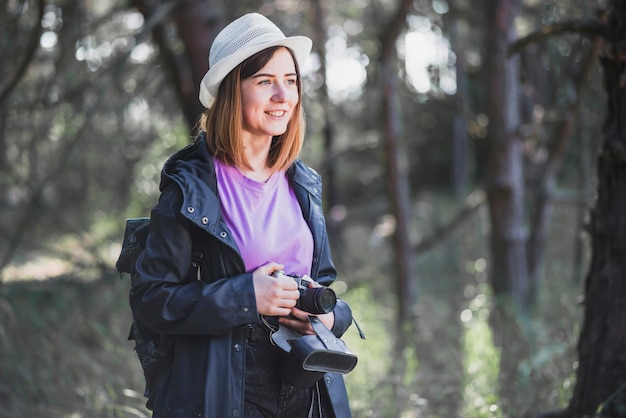 Mujer alegre con cámara en el bosque