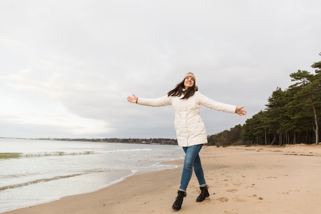 Mujer alegre caminando cerca del agua de mar