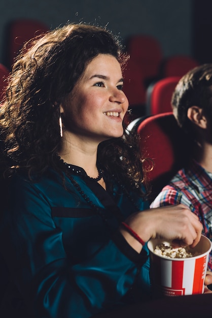 Mujer alegre comiendo palomitas de maíz en el cine