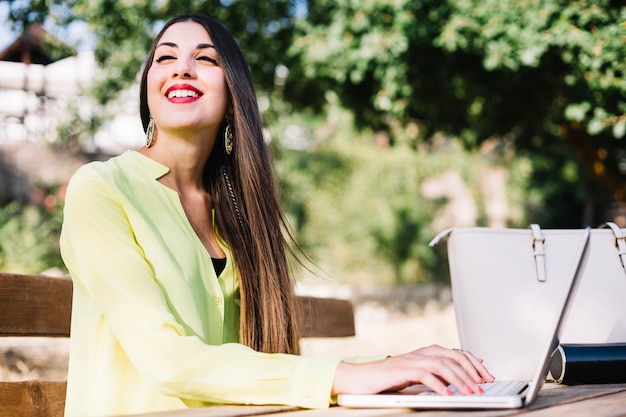 Mujer alegre en la computadora portátil