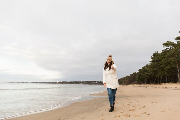 Mujer alegre en la costa apuntando a la cámara