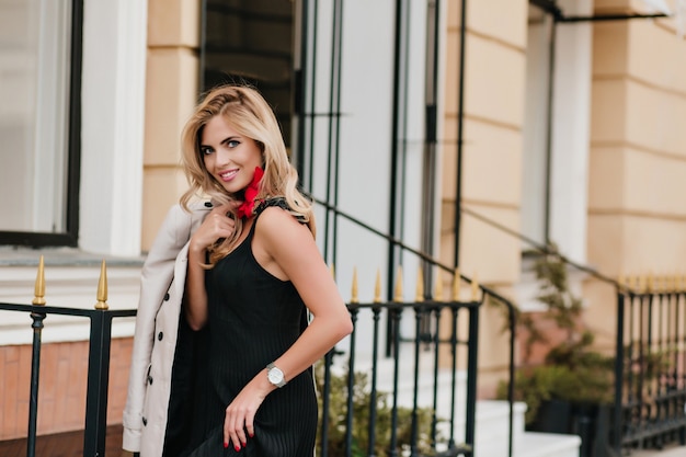 Foto gratuita mujer alegre delgada en reloj de pulsera blanco de moda riendo mientras posa junto a la tienda