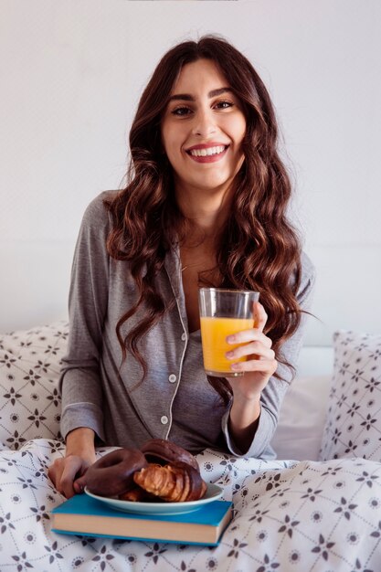 Mujer alegre desayunando en la cama