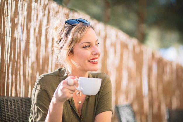 Mujer alegre disfrutando de bebida en vacaciones