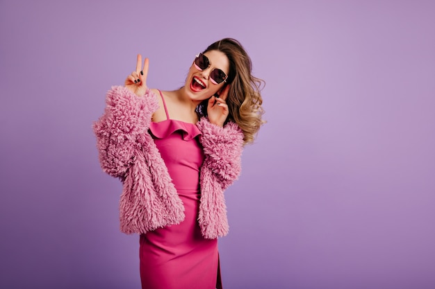 Mujer alegre en elegantes gafas de sol oscuras posando en estudio