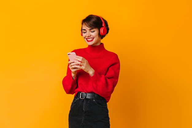 Mujer alegre escuchando música y mirando smartphone