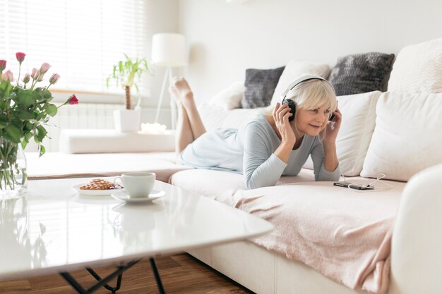 Mujer alegre escuchando música en el sofá