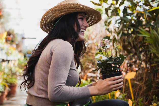 Mujer alegre con flor en maceta