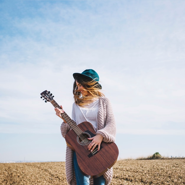 Mujer alegre con guitarra en el campo