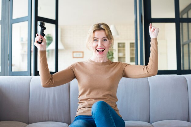 Mujer alegre con joystick en el sofá