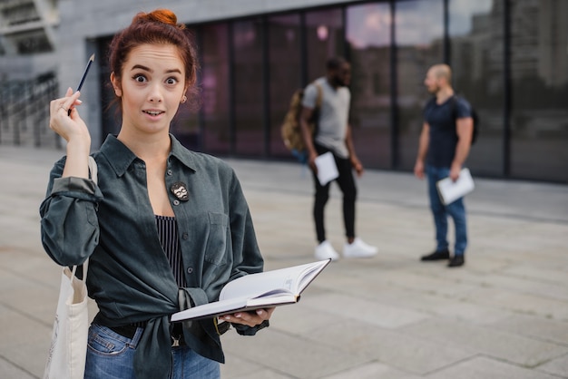 Mujer alegre con lápiz y libro