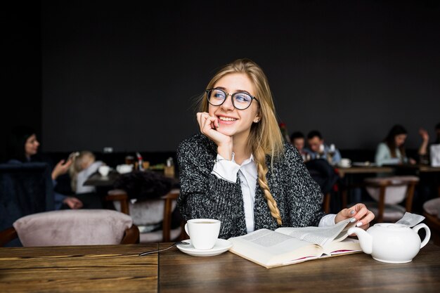 Mujer alegre con libro en café
