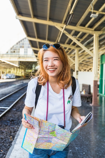 Foto gratuita mujer alegre con mapa en plataforma