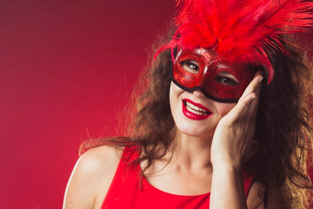 Mujer alegre en máscara roja con plumas