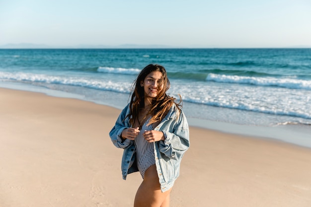 Foto gratuita mujer alegre en la orilla del mar mirando a cámara