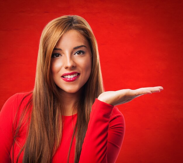 Mujer alegre con la palma de la mano abierta sobre fondo rojo