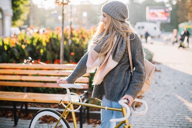 Mujer alegre de pie cerca de la bicicleta