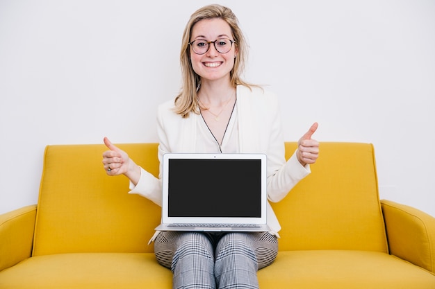 Foto gratuita mujer alegre con portátil gesticular pulgar arriba