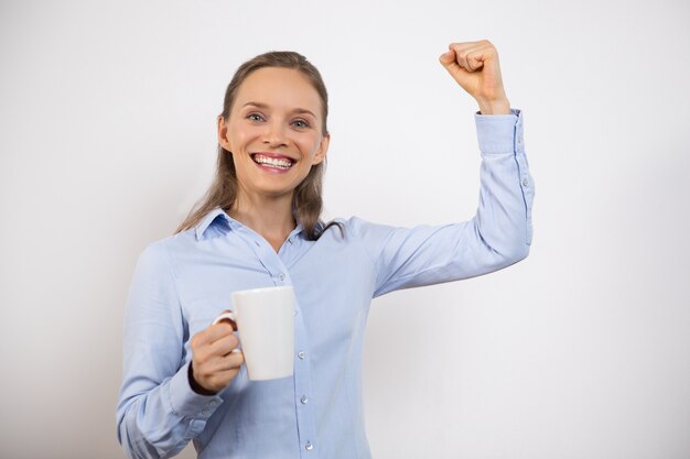 Mujer alegre que celebra éxito y que bebe té