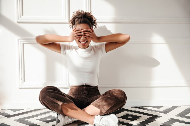 Mujer alegre que cubre los ojos con las manos