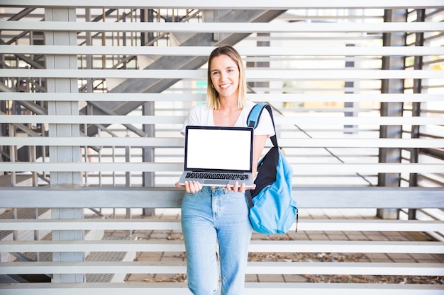 Foto gratuita mujer alegre que muestra la computadora portátil a la cámara