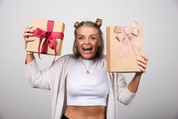 Mujer alegre que muestra los regalos navideños con expresión feliz.