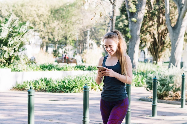 Mujer alegre que usa smartphone durante el entrenamiento