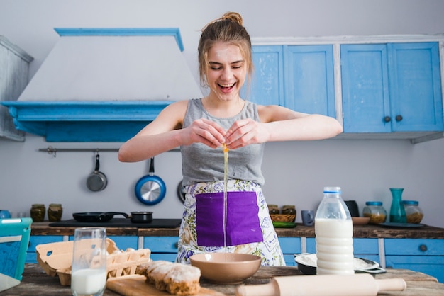 Foto gratuita mujer alegre rompiendo huevos sobre el tazón