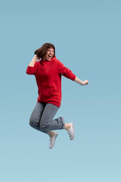 Mujer alegre saltando aislado en azul