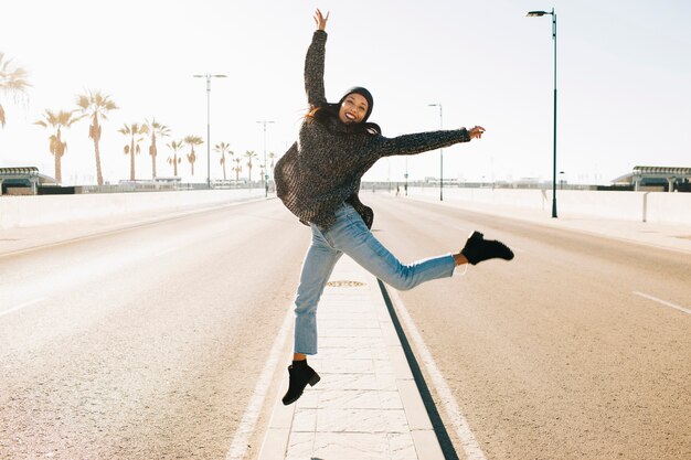 Mujer alegre saltando en medio de la calle