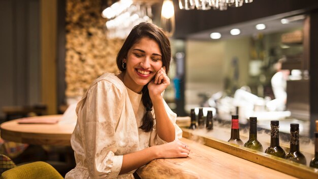 Mujer alegre sentada en barra de bar