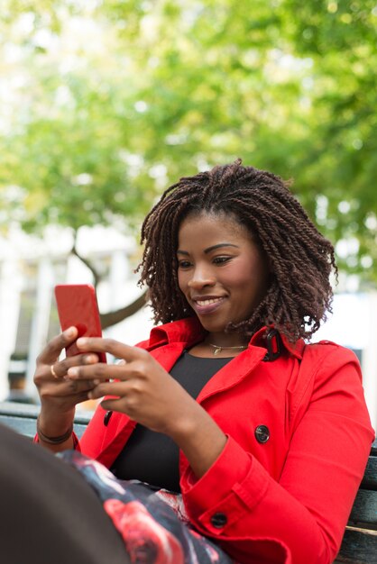 Mujer alegre con smartphone en la calle