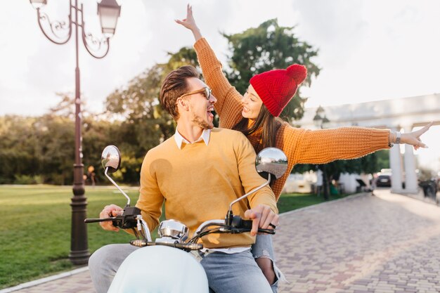 Mujer alegre con sombrero rojo divertido disfrutando de una unidad extrema con su novio