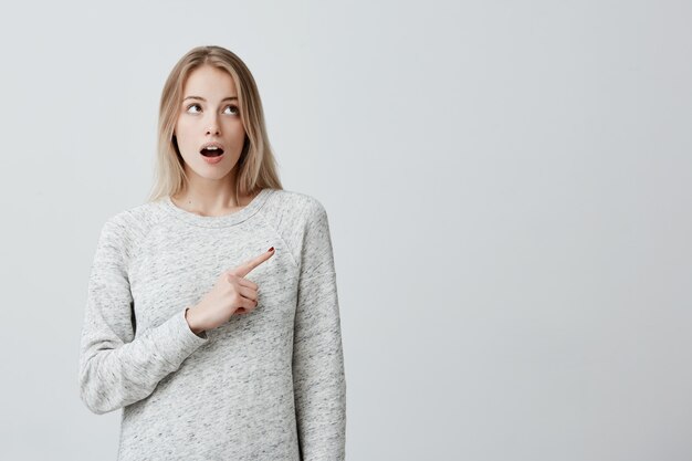 Mujer alegre sonriente que señala con el dedo en copyspace